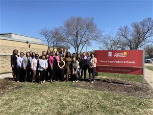 Large group posing next to red Career Pathways sign outside of building